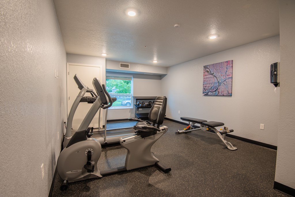 A gym room with treadmills, exercise bikes, and a television.