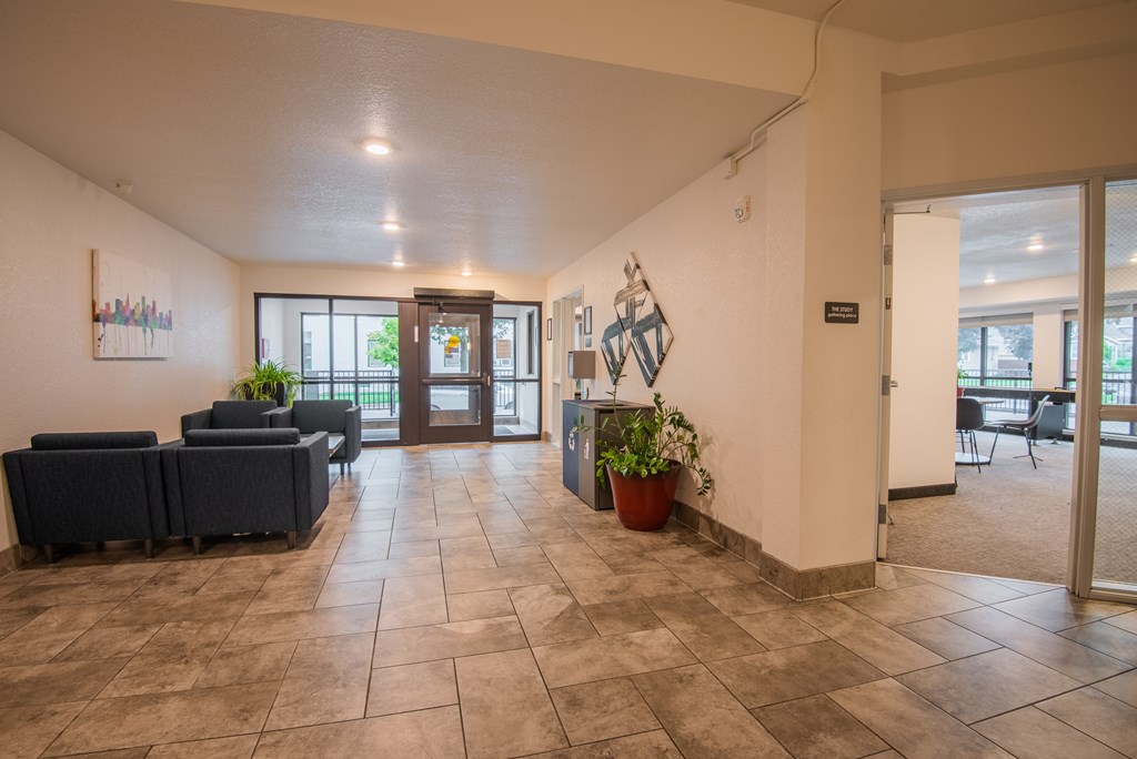A spacious lobby with a couch, potted plant, and a painting on the wall.