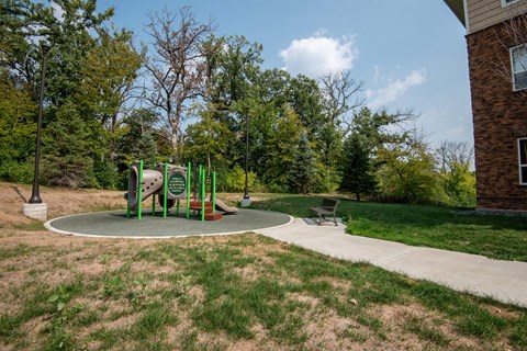 A playground with a green slide and a brown bench.