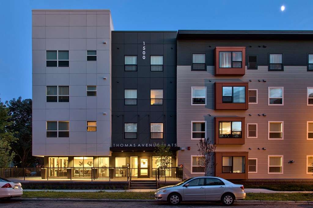 A modern apartment building named Thomas Avenue is shown with a car parked in front.