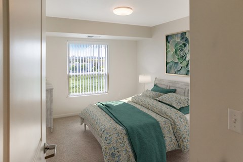 A bedroom with a bed, nightstand, and window.