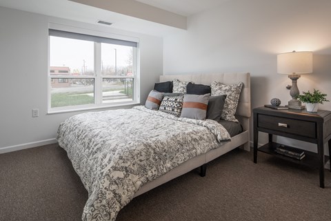 A bedroom with a large bed and a nightstand with a lamp.