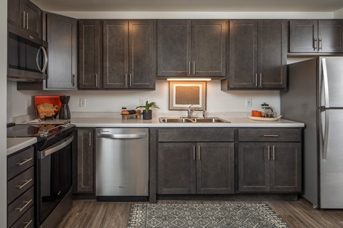 A modern kitchen with dark wood cabinets and stainless steel appliances.