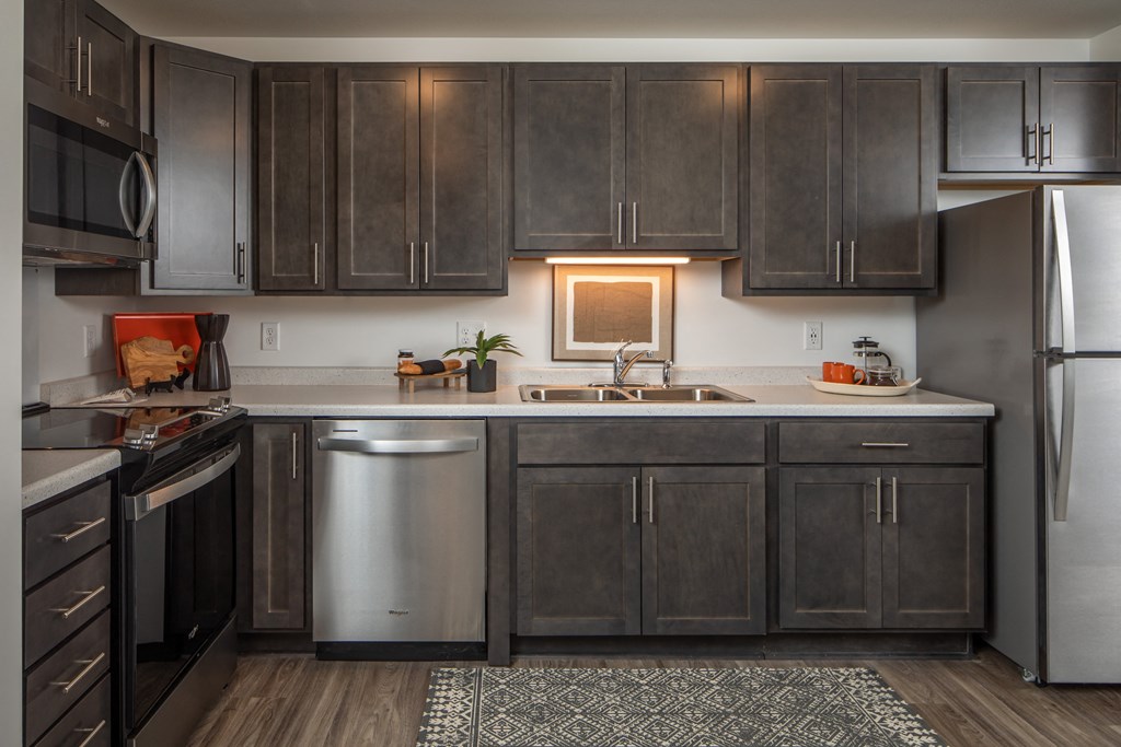 A modern kitchen with dark wood cabinets and stainless steel appliances.
