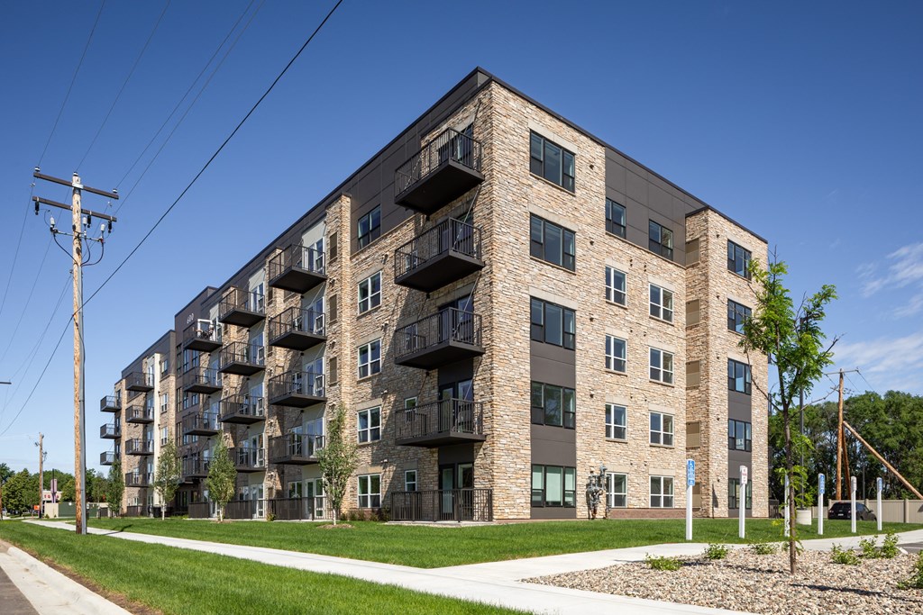 a brick apartment building with balconies and a sidewalk