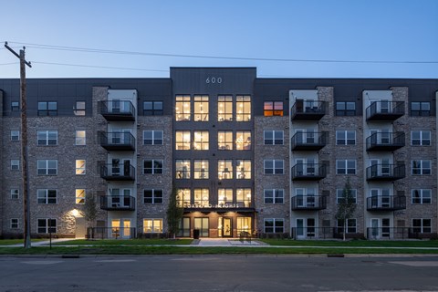 an apartment building with its windows lit up at dusk