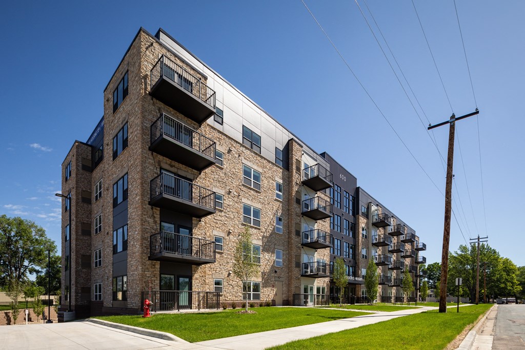 a brick apartment building with balconies and a green lawn