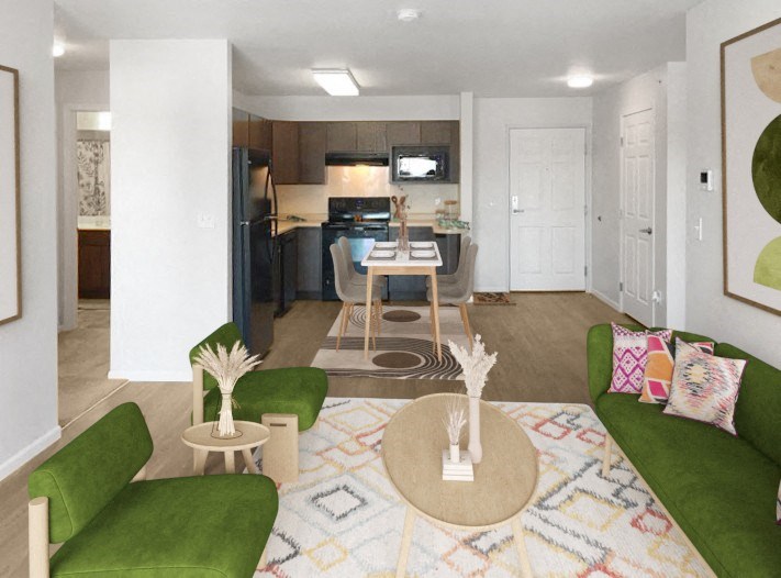 a living room and kitchen with green couches and chairs and a rug