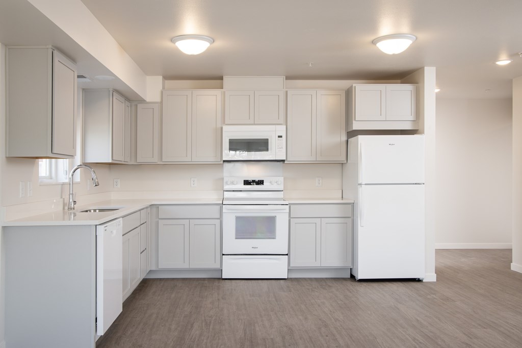 A white kitchen with a refrigerator, oven, and microwave.