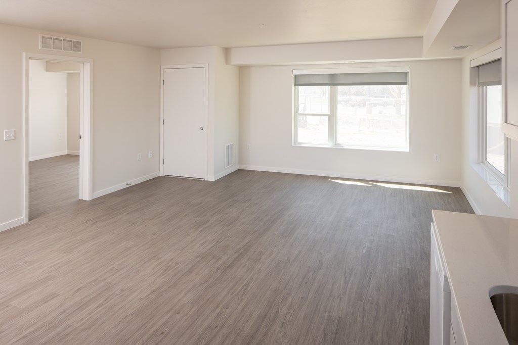 A spacious room with light wood flooring and white walls.