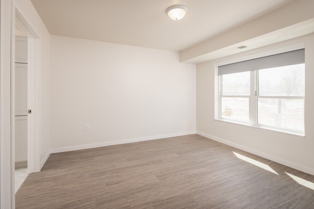 A room with a window and a wooden floor.