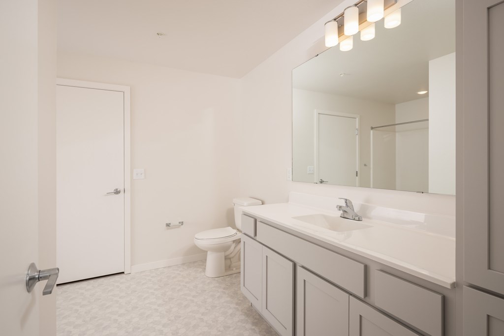 A white bathroom with a toilet, sink, and mirror.