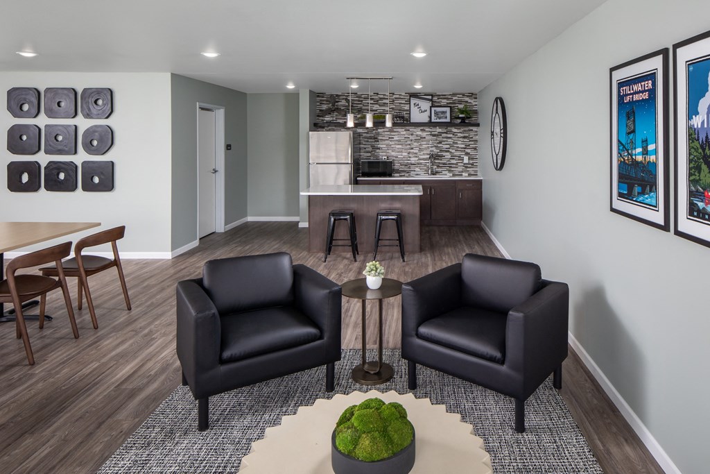 Two black leather chairs are placed in a room with a green plant on the table between them.
