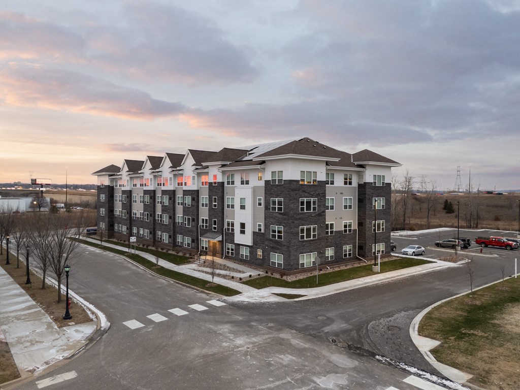 A large apartment complex with a parking lot in front.