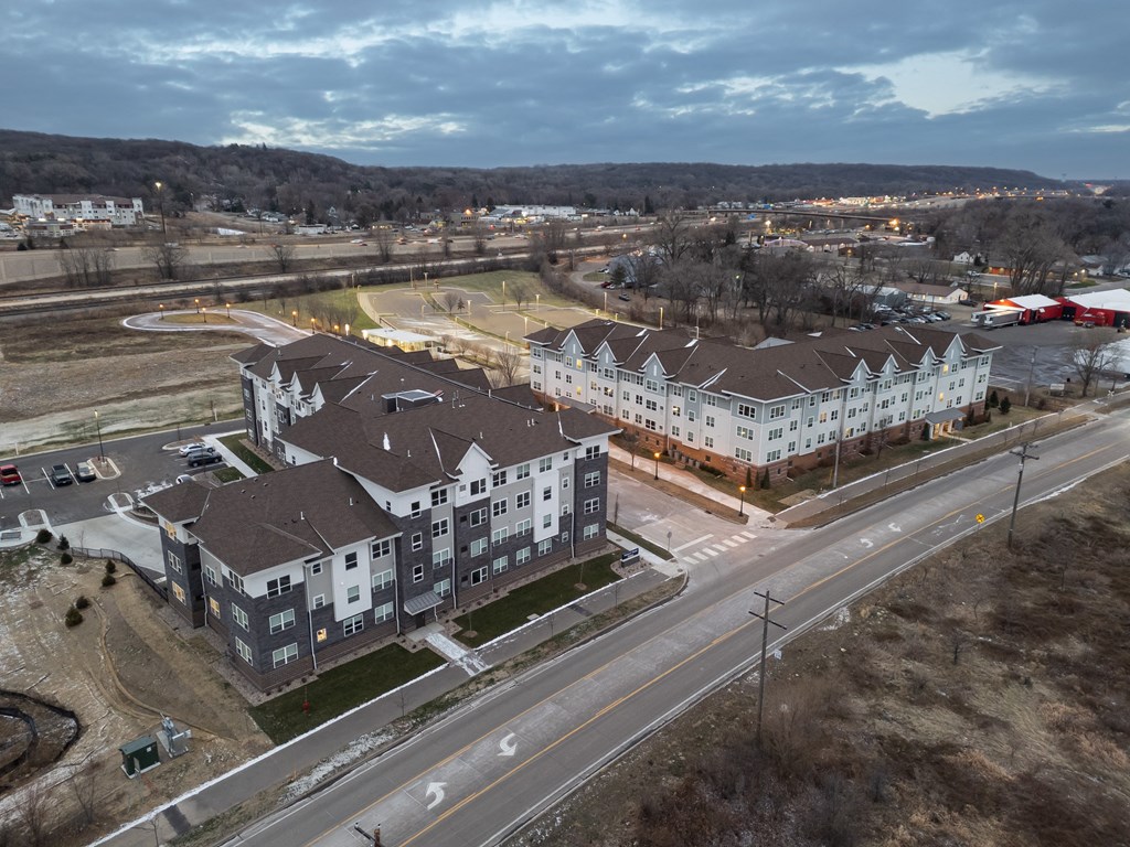 A large apartment complex is surrounded by a road and a field.
