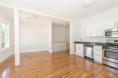 A kitchen with white cabinets and a wooden floor.