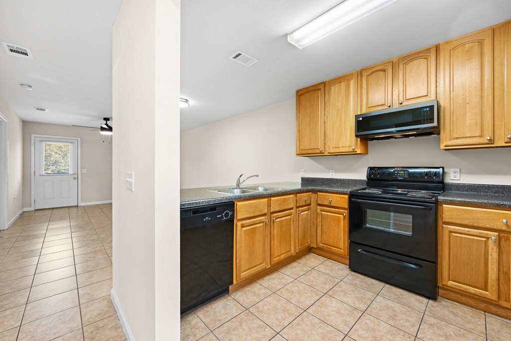A kitchen with black appliances and wooden cabinets.