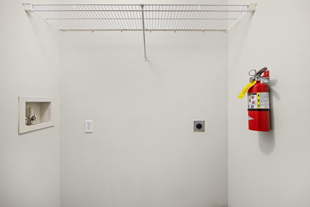 A red fire extinguisher is mounted on a white wall.
