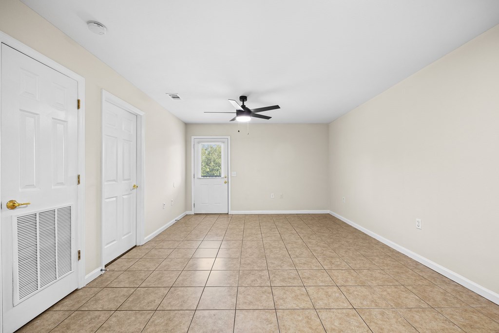 A room with a ceiling fan and tile flooring.