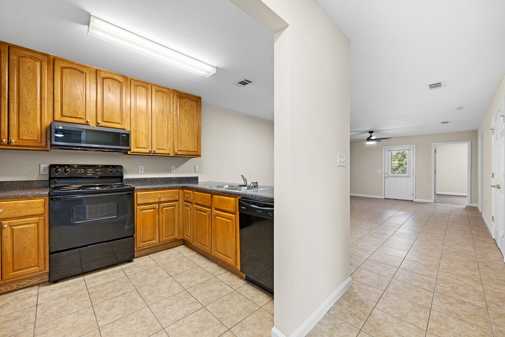 A kitchen with wooden cabinets and black appliances.