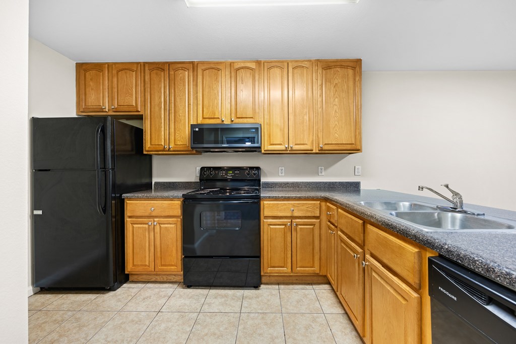 A kitchen with black appliances and wooden cabinets.