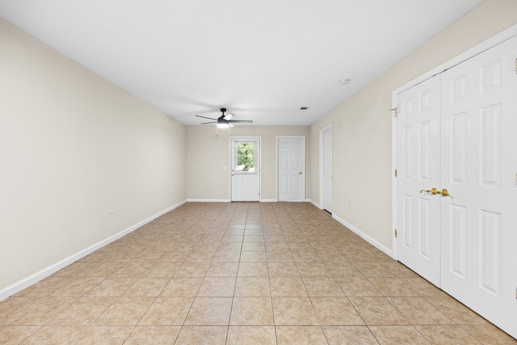 A room with a white ceiling fan and tile flooring.