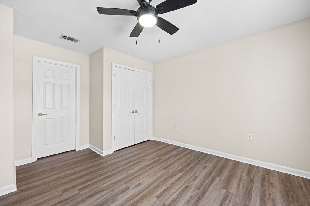 A room with a ceiling fan and two doors.