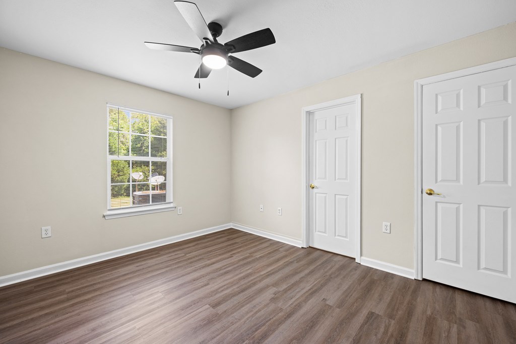A room with a ceiling fan and two doors.