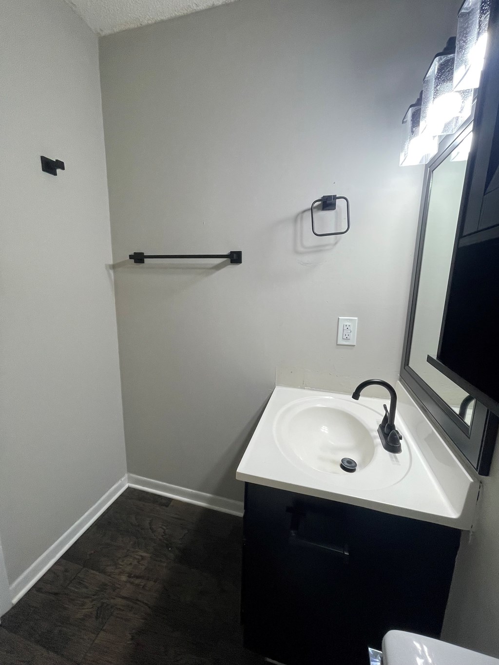 A bathroom with a white sink and black towel rack.