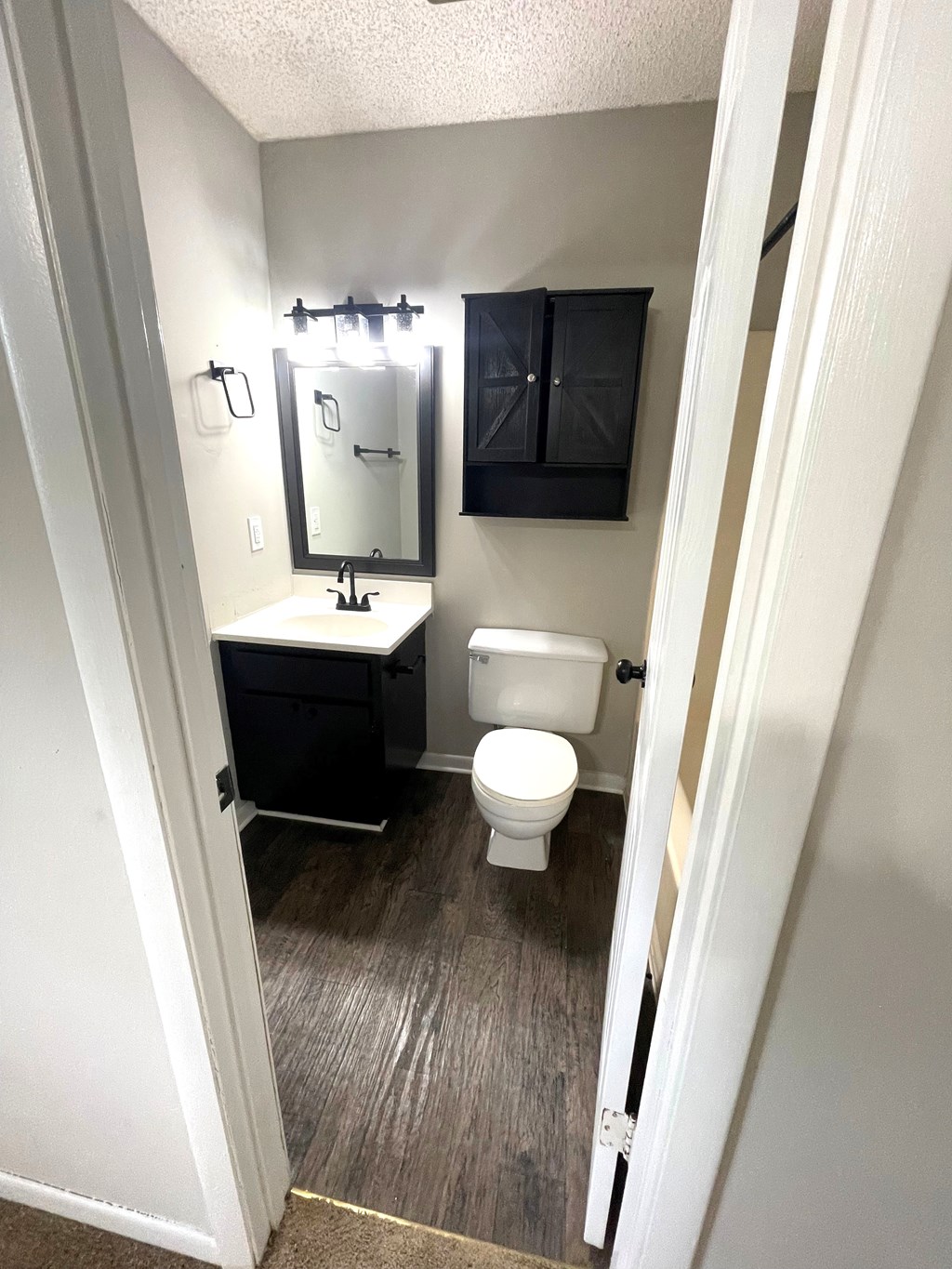 A bathroom with a toilet, sink and mirror.