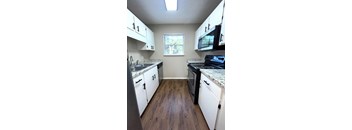 A kitchen with white cabinets and a window.