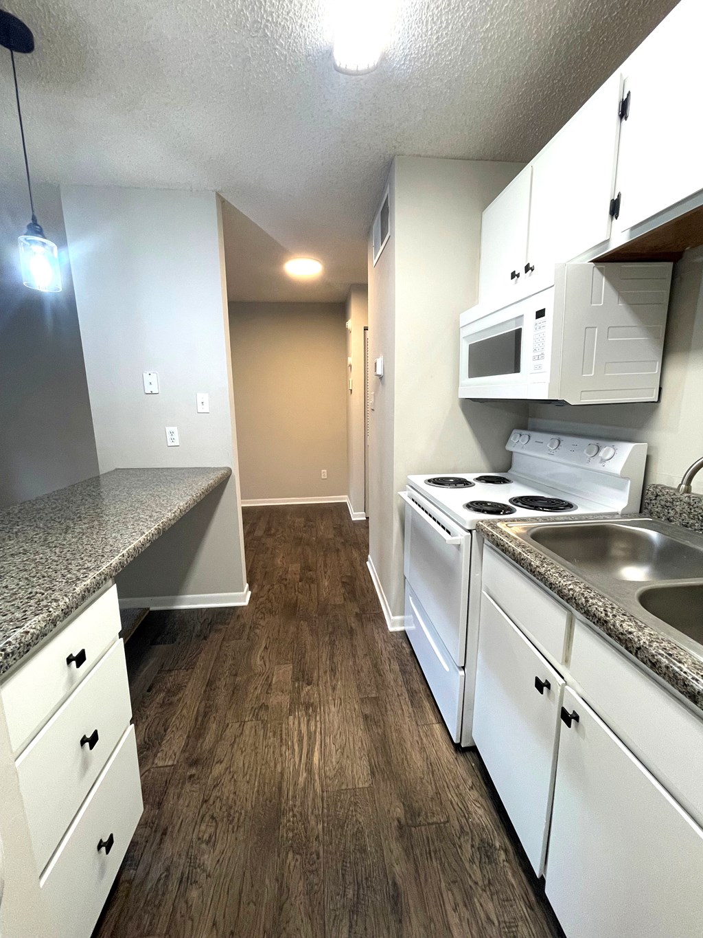 A kitchen with white cabinets and a granite countertop.