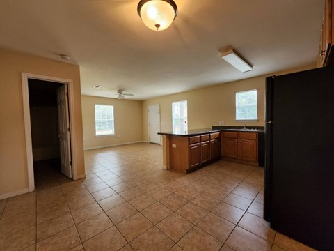 A kitchen with brown cabinets and a black refrigerator.
