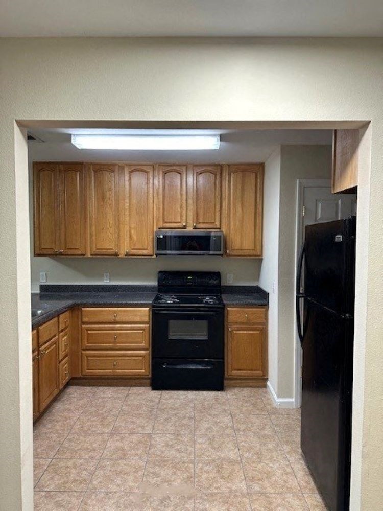 A kitchen with black appliances and wooden cabinets.