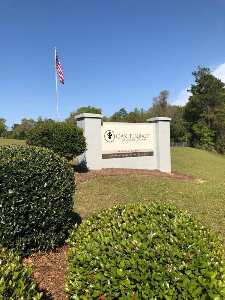 A sign that says Oak Terrace in front of a flag.