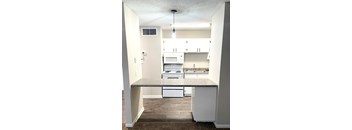 A kitchen with white cabinets and a granite counter.