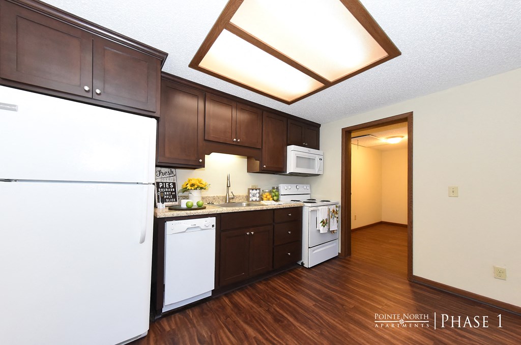a kitchen with white appliances and dark wood cabinets