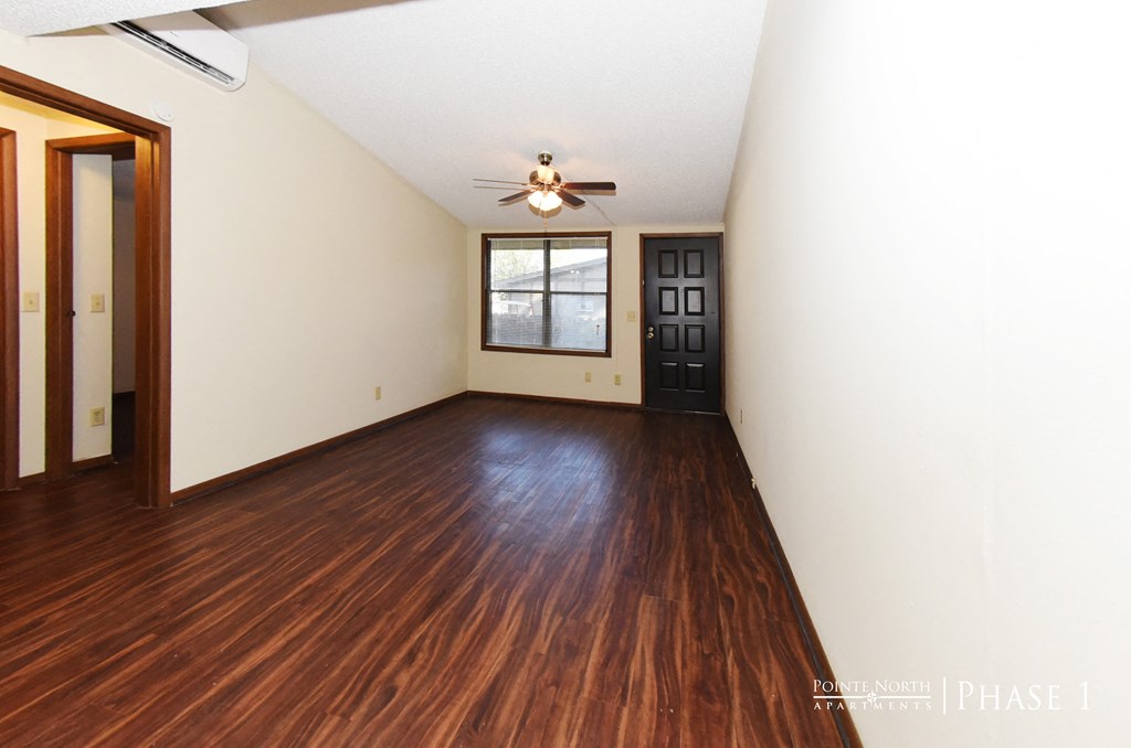 an empty living room with wooden floors and a ceiling fan