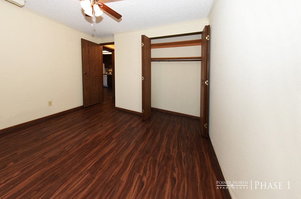 an empty living room with wood flooring and a closet