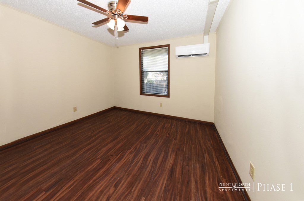 an empty room with wooden floors and a ceiling fan