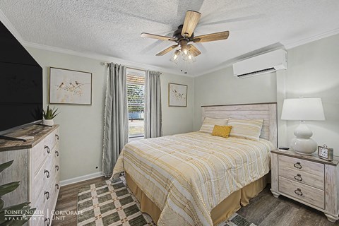 A bedroom with a bed, dresser, and ceiling fan.