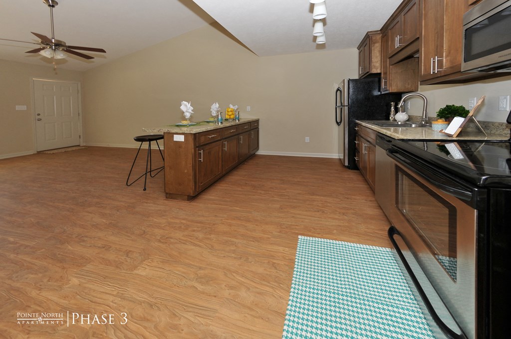 a kitchen with black appliances and wood floors