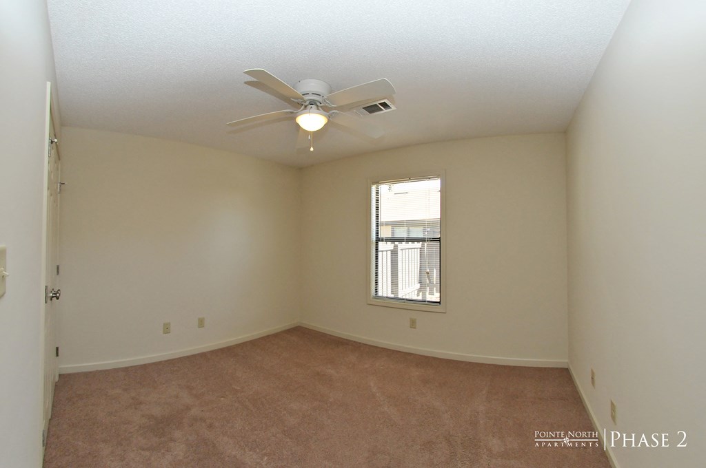 an empty living room with a ceiling fan and a window