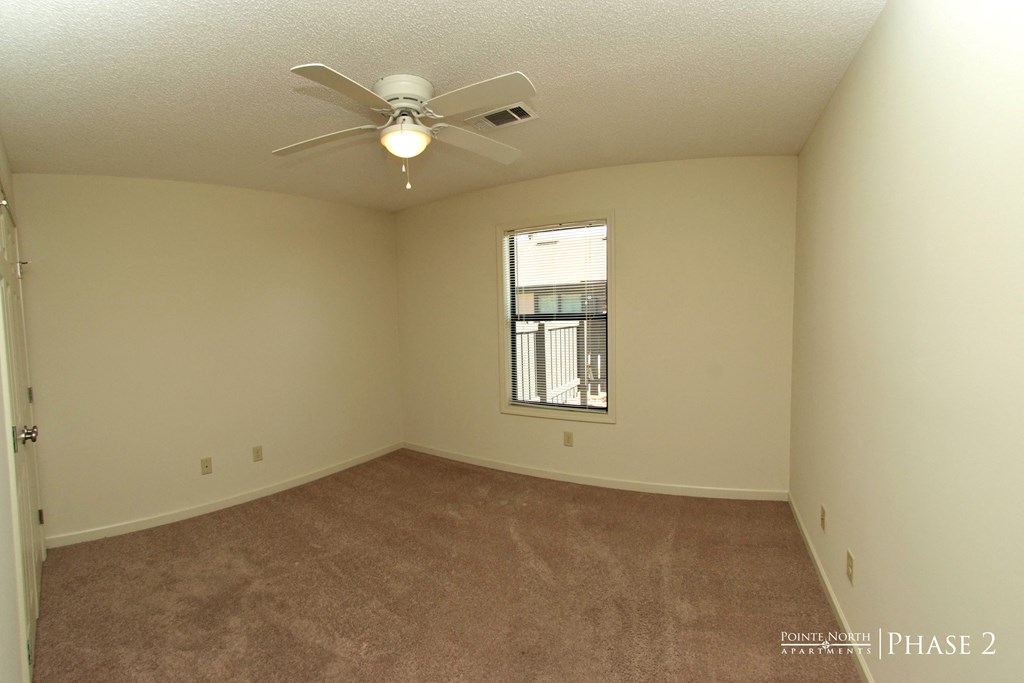 an empty living room with a ceiling fan and a window