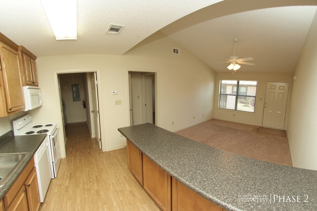 an empty kitchen and living room with a granite counter top