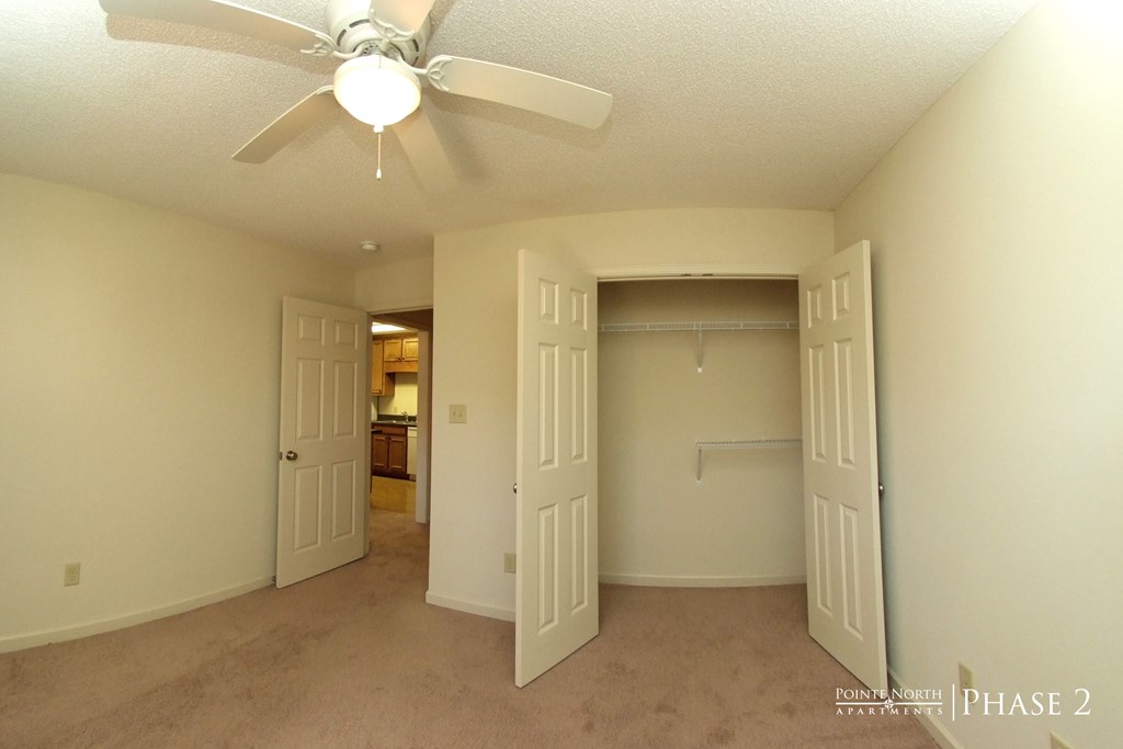 a bedroom with a closet and a ceiling fan