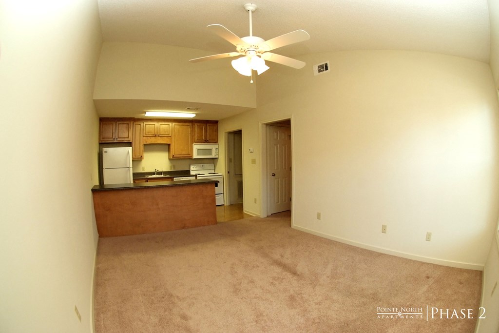 an empty living room and kitchen with a ceiling fan