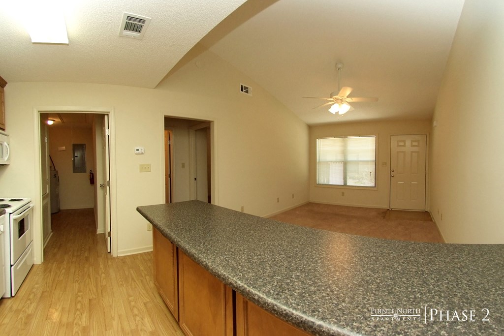 an empty kitchen and living room with a granite counter top