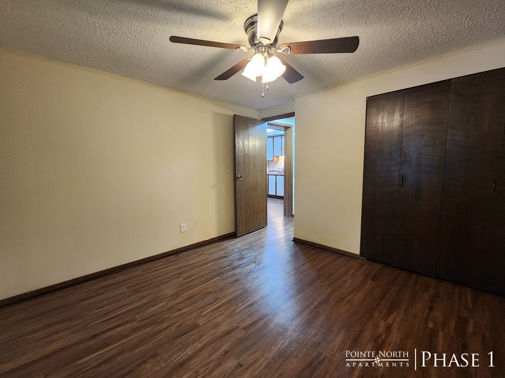 an empty living room with wood floors and a ceiling fan