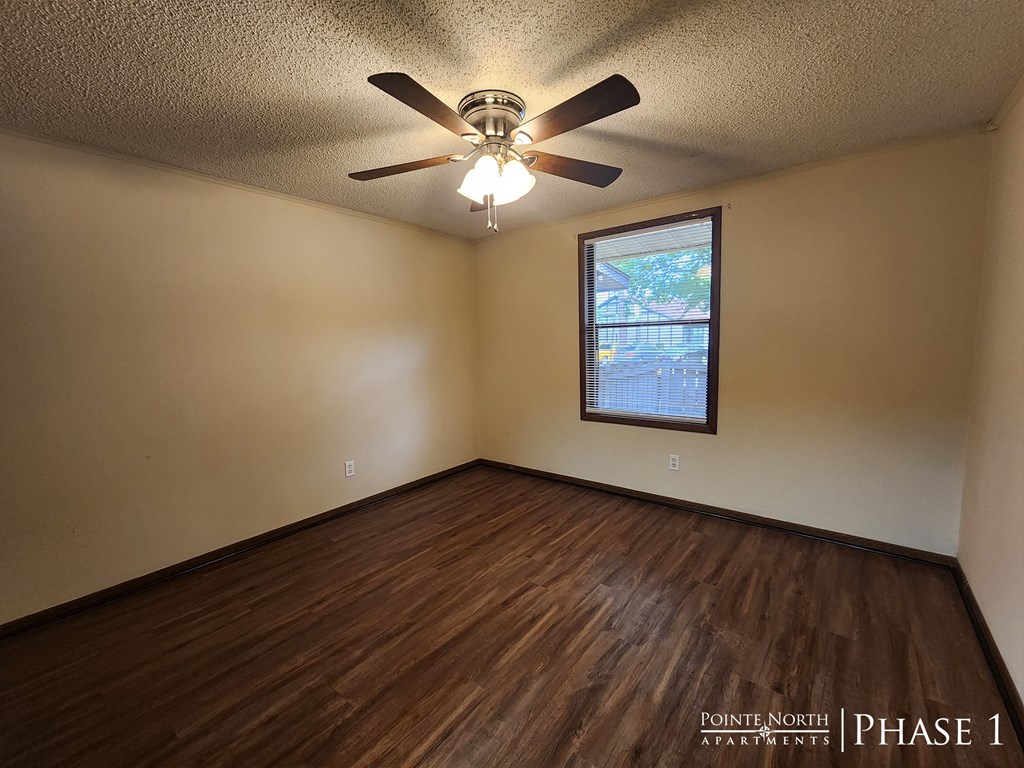 the living room of a home with wood floors and a ceiling fan